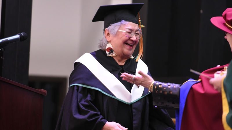 Julia Adams prepares for a congratulatory hug while crossing the stage during Wilp Wilxo'oskwhl Nisga'a Institute's Convocation in Gitwinksihlkw. 